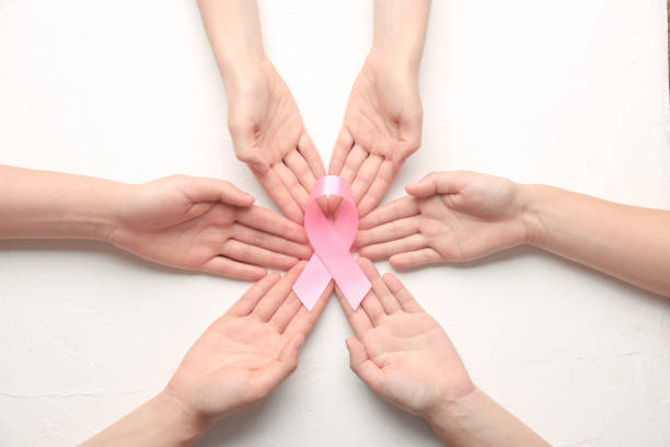 Female hands holding pink ribbon on white background. Breast cancer awareness concept stock photo
