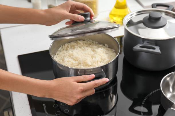 Woman cooking rice on stove in kitchen stock photo
