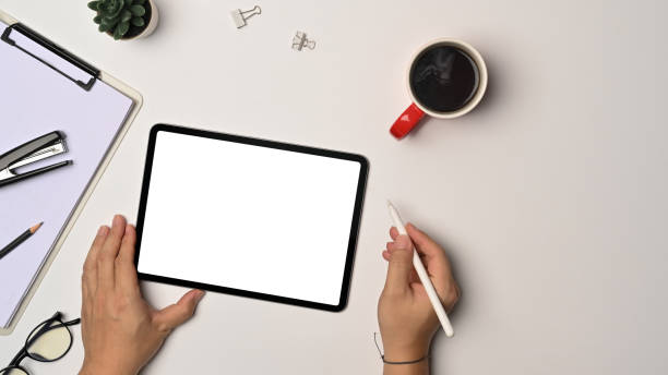 istock Above view man holding stylus pen and using digital tablet on white office desk. 1350764253