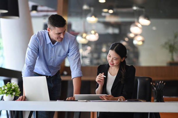 istock Two business colleagues checking financial reports and discussing project together at office. 1350764329