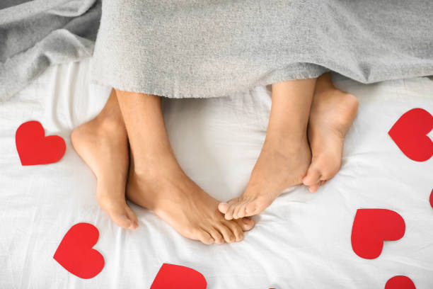 Legs of young couple lying on bed stock photo