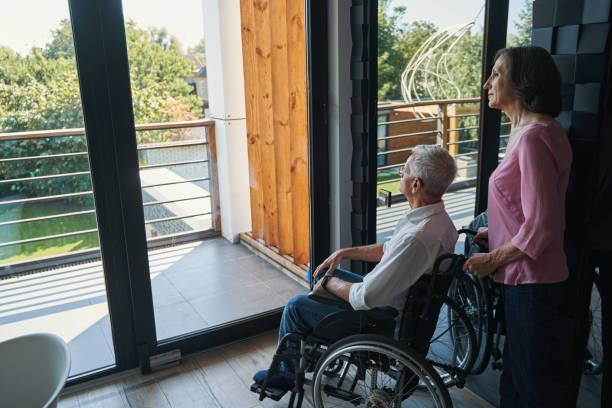 istock Man with disability in wheelchair looking at yard from window 1350766053