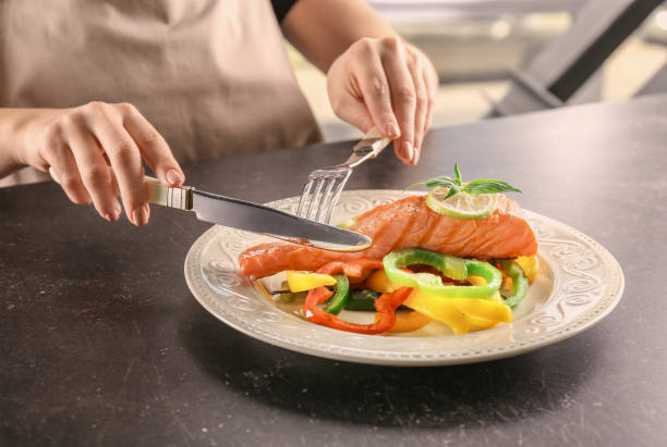 mulher comendo salmão saboroso com pimentas frescas à mesa - cooked pepper salmon food - fotografias e filmes do acervo