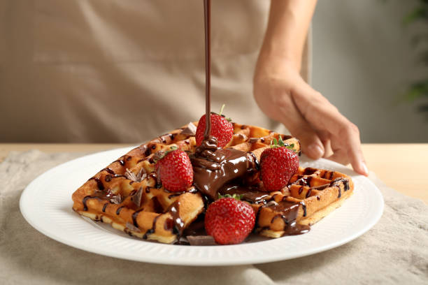 mulher derramando molho de chocolate em waffles caseiros saborosos, close-up - waffle breakfast syrup food - fotografias e filmes do acervo