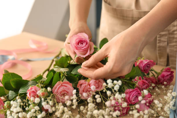 Female florist preparing bouquet of beautiful flowers at table, closeup stock photo