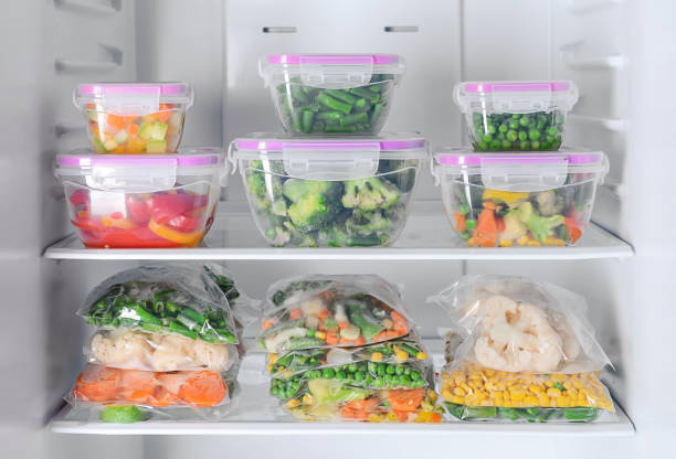 istock Containers and plastic bags with frozen vegetables in refrigerator 1350767787