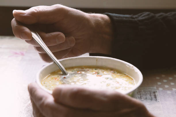 istock An elderly man is eating noodle soup holding a spoon in one hand 1350768663