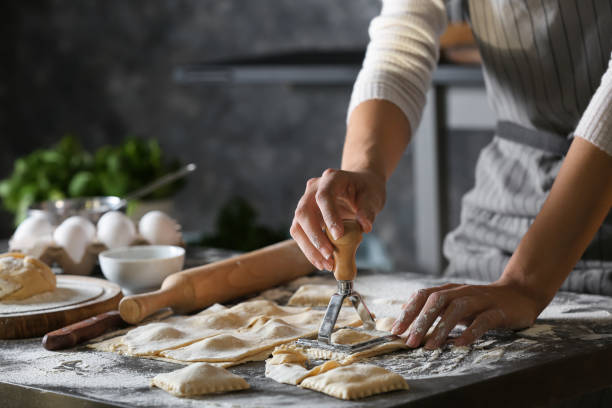 Woman making tasty ravioli on table stock photo