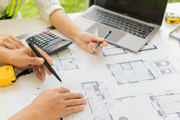 istock Two male and female engineers working on blueprints for the project worked with partners to create models and engineering tools in the house building concepts office. 1350771355