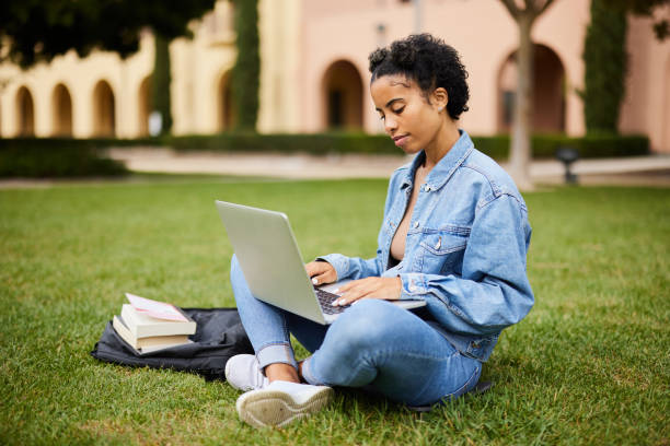 istock Female university student sitting outside on campus and working on a laptop 1350776790