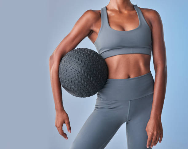 студийный снимок подтянутой женщины, треномися с мячом для медицины на сером фоне - abdomen abdominal muscle muscular build beautiful стоковые фото и изображения