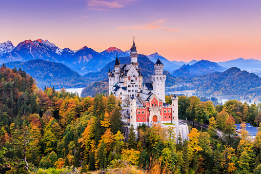 Germany, Neuschwanstein Castle. View of the castle and the Bavarian Alps at sunrise during fall season.