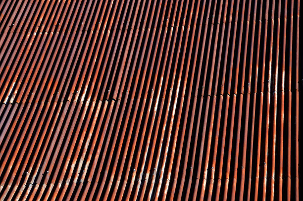 istock corrugated iron roof with a lightning conductor on top. the sheet is the whole rust and forms a texture similar to Manchester fabric. roof before renovation, blue sky 1350780182