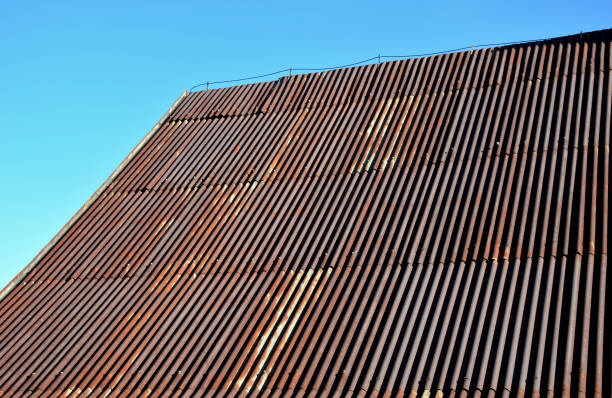 istock corrugated iron roof with a lightning conductor on top. the sheet is the whole rust and forms a texture similar to Manchester fabric. roof before renovation, blue sky 1350780326
