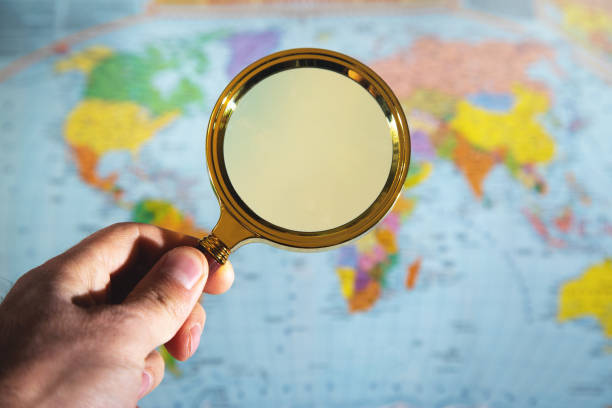 istock Male hand hold a magnifying glass over the world map. 1350780396