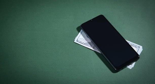 istock Smartphone and money on green background. 1350780433