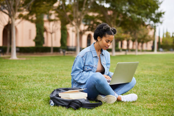 istock Female college student doing homework on a laptop on campus lawn 1350781869