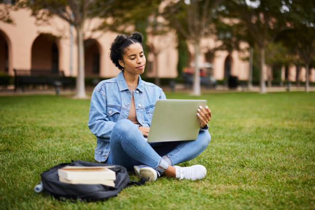 istock Female college student sitting on campus and doing homework on a laptop 1350782071