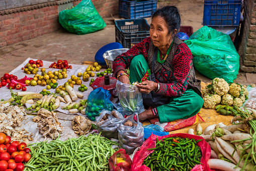 Female Indian street  sellers selling vegetables on the streets of Bhaktapur, Nepal. Bhaktapur is an ancient town in the Kathmandu Valley and is listed as a World Heritage Site by UNESCO for its rich culture, temples, and wood, metal and stone artwork.
