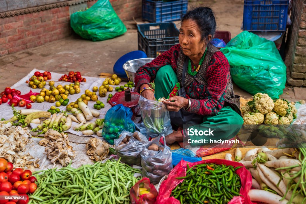 Indian street sellers selling vegetables in Bhaktapur, Nepal Female Indian street  sellers selling vegetables on the streets of Bhaktapur, Nepal. Bhaktapur is an ancient town in the Kathmandu Valley and is listed as a World Heritage Site by UNESCO for its rich culture, temples, and wood, metal and stone artwork. Poverty Stock Photo