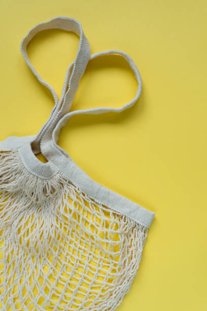 istock Knitted string bag on a yellow background. Heart shaped handles. 1350785263