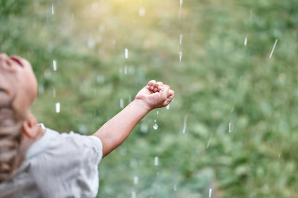 istock Little boy enjoys warm summer rain on meadow in backyard 1350785466