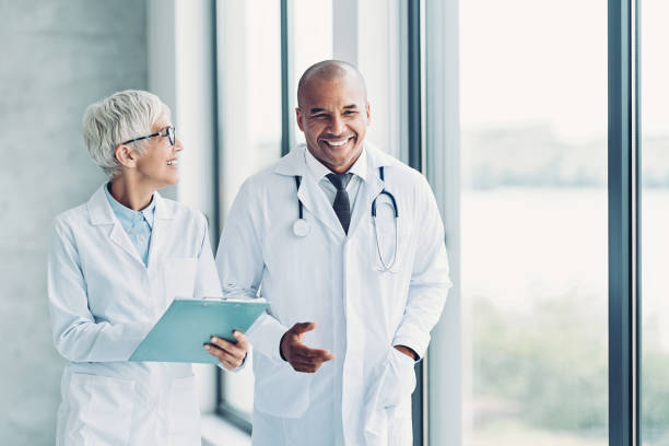 Two doctors walking side by side and discussing a medical record stock photo