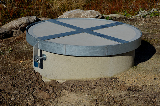 concrete well well covered with a round concrete lid. a fall into a well often ends tragically with drowning, suffocation or fractures. the lock and the metal frame ensure the opening of the hatch, grille, hatch, supply, vault,