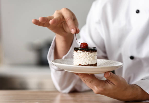 Male chef with tasty dessert in kitchen, closeup stock photo