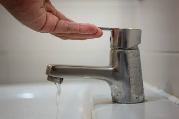 People hand is opening water faucet - Interior object using action. Action of people hand is opening water faucet at hand washing sink in bathroom. Close-up and selective focus. flushing valve public restroom toilet stock pictures, royalty-free photos & images