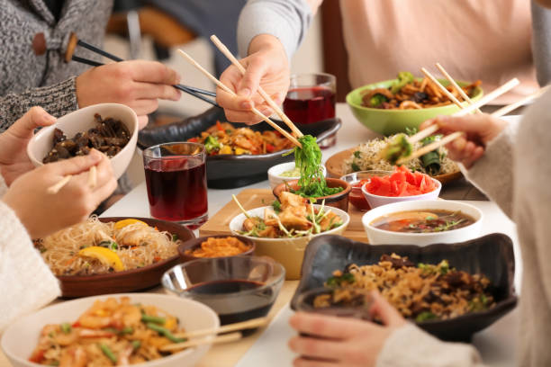 Friends eating tasty Chinese food at table stock photo