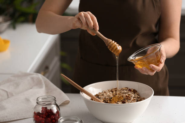 Woman making tasty granola bars in kitchen stock photo