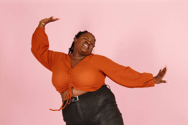 istock Excited young black plus size woman dances on pink background 1350787899