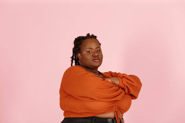 Young confident black woman looks at camera on pink background stock photo
