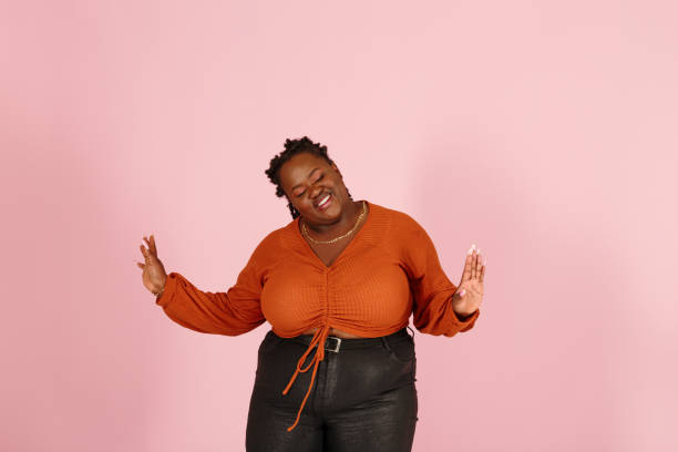 istock Excited young black plus size woman dances on pink background 1350788227