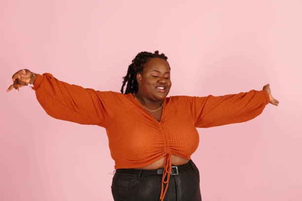 istock Excited young black plus size woman dances on pink background 1350788228