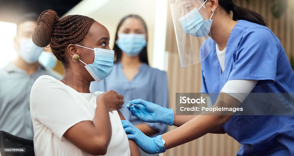 Cropped shot of an attractive young businesswoman getting her covid vaccination from a female nurse in the office Getting her booster shot Vaccination Stock Photo