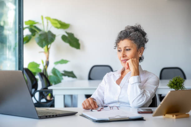 istock Senior gray haired woman looking at computer in office 1350790461