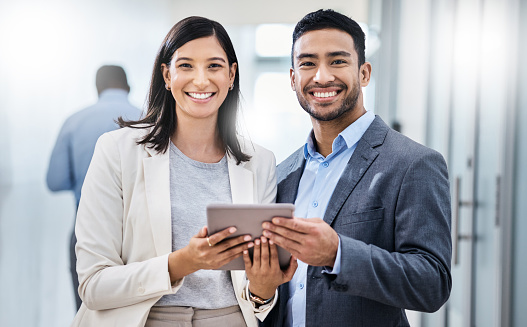 Shot of two businesspeople standing together and holding a digital tablet in an office