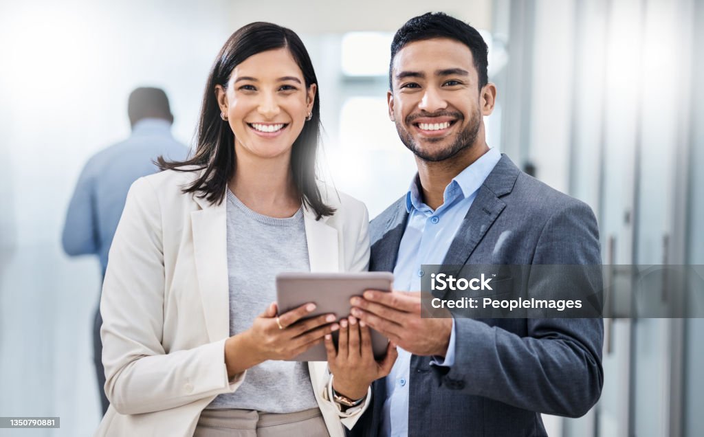 Shot of two businesspeople standing together and holding a digital tablet in an office Big things have small beginnings Business Person Stock Photo