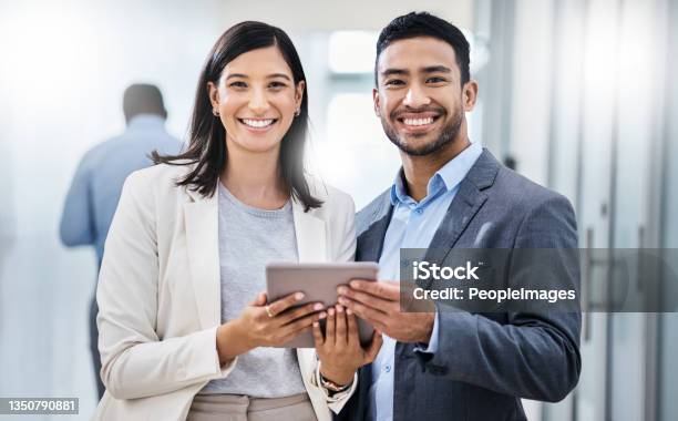Shot Of Two Businesspeople Standing Together And Holding A Digital Tablet In An Office Stock Photo - Download Image Now