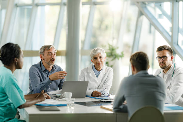 grupo de médicos y empresarios hablando en una reunión en el consultorio del médico. - adminstrator fotografías e imágenes de stock