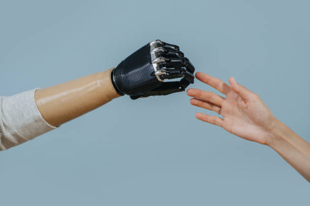 istock Two hands, living and bionic reaching for each other. Over blue background. 1350792157