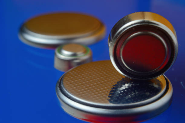istock small button batteries of different sizes, highlighted in red and orange, lie against a blue background. close-up. 1350792294