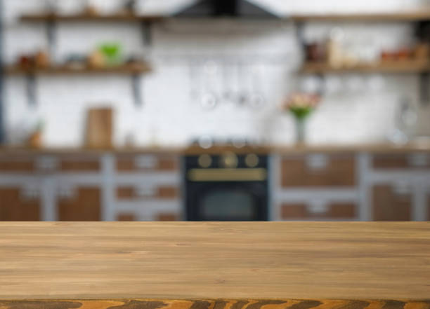 istock Wooden table with free space and blurred kitchen on the background. 1350793867