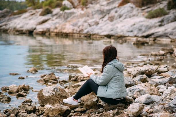 istock Young Woman Reading a Book on the Beach 1350793937