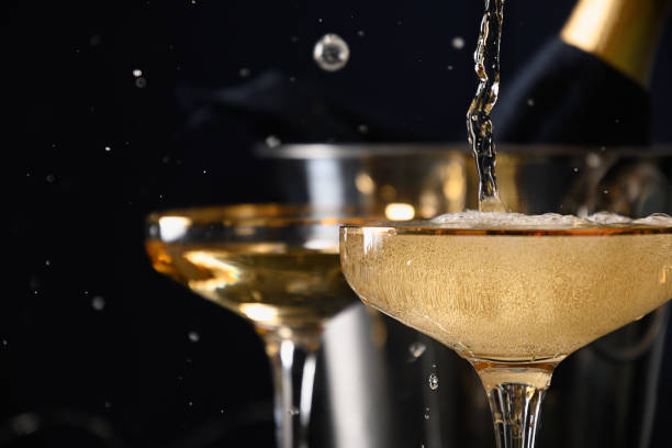champagner in weingläser auf schwarz gießen. neujahrsfeier 2022. - champagne stock-fotos und bilder