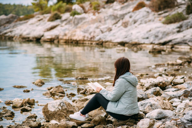 istock Young Woman Reading a Book on the Beach 1350795167