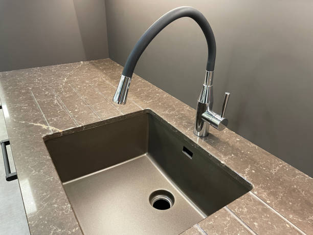 istock Close-up image of modern, rectangular, bronze toned kitchen sink, integrated brown grooved granite draining board, black rubber omni-directional, single lever kitchen tap 1350795206