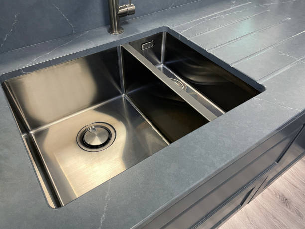 istock Image of modern, rectangular, stainless steel kitchen sink with 1.5 bowl sink and integrated draining board, stainless steel, single lever monobloc mixer tap, elevated view, focus on foreground 1350795260